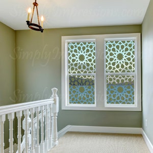 May include: Two windows with white frames and a green wall behind them. The windows have a geometric pattern on the glass, with a light blue, white, and green color scheme.