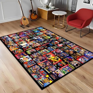 May include: A rectangular rug displaying a collage of colourful video game cartridge box art. The rug has a black border and is placed on a wooden floor. The rug's design includes various game titles and vibrant graphics.