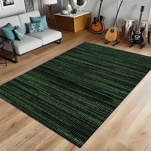 Op de afbeelding: Een rechthoekig vloerkleed met een zwarte achtergrond en een patroon van groene stippen en lijnen. Het vloerkleed ligt op een houten vloer. Dit vloerkleed is een woondecoratie-artikel.