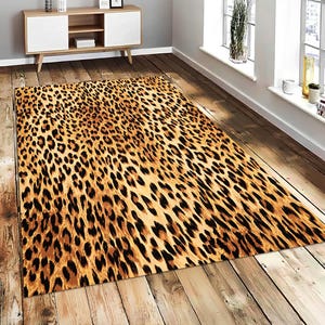May include: A rectangular area rug featuring a repeating leopard print pattern in shades of golden tan, brown, and black. The rug has a low-profile texture and covers a portion of the wooden floor, displaying a consistent animal-inspired design.