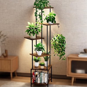 May include: A tall, multi-tiered plant stand featuring a black metal frame and dark wood-grain shelves. The unit holds several potted green plants of varying sizes, including a hanging plant, and includes a bottom shelf for storing books.
