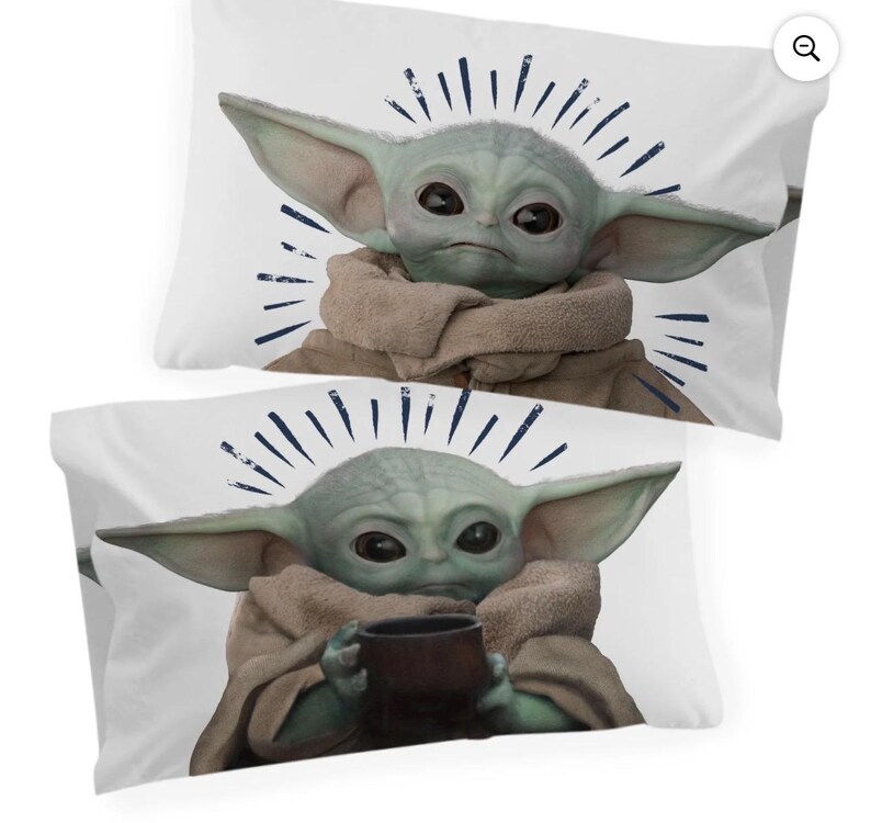May include: Two white pillowcases featuring a green alien character with large ears and dark eyes. The character is wearing a brown robe and holding a dark brown cup. Blue lines radiate from the character's head.