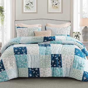 May include: A patchwork quilt and matching pillowcases in shades of blue, teal, and white. The quilt features a floral pattern and square blocks. The bed is made up with a decorative pillow and two standard pillows.
