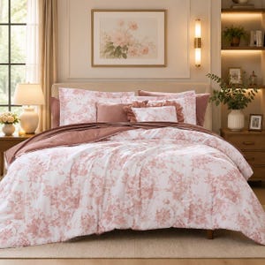 May include: A bedding set featuring a white comforter and matching pillow shams with a dusty rose floral pattern. The set includes solid dusty rose accent pillows and a ruffled decorative pillow, all arranged on a bed with a neutral headboard.