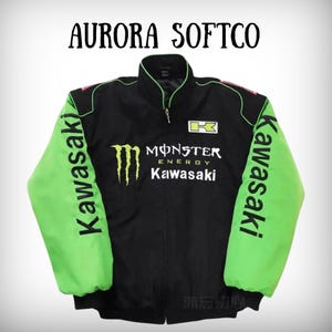 May include: Black and green Kawasaki jacket with the text "AURORA SOFTCO" at the top. The jacket features the Monster Energy logo and Kawasaki branding. The sleeves are bright green, and the jacket has a zipper closure.