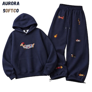 K&ouml;nnte beinhalten: Ein marineblaues Set aus Kapuzenpullover und Jogginghose mit gestickten Dackeln. Der Hoodie hat eine K&auml;ngurutasche und einen Dackel mit rotem Barett. Die Hose verf&uuml;gt &uuml;ber einen elastischen Kordelzug am Bund und elastische Beinabschl&uuml;sse.