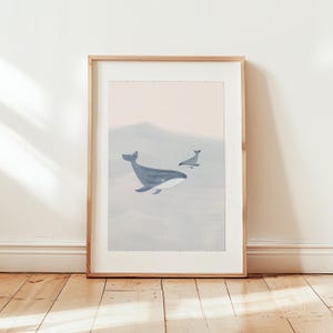 K&ouml;nnte beinhalten: Ein gerahmter Druck eines Aquarells, das zwei Wale zeigt, die in einem hellblauen und rosafarbenen Ozean schwimmen. Der gr&ouml;&szlig;ere Wal befindet sich im Vordergrund, w&auml;hrend der kleinere Wal im Hintergrund ist.
