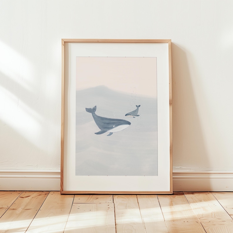 K&ouml;nnte beinhalten: Ein gerahmter Druck eines Aquarells, das zwei Wale zeigt, die in einem hellblauen und rosafarbenen Ozean schwimmen. Der gr&ouml;&szlig;ere Wal befindet sich im Vordergrund, w&auml;hrend der kleinere Wal im Hintergrund ist.