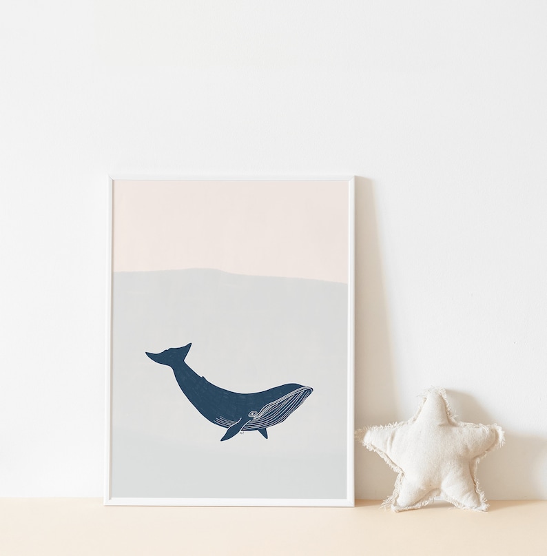 May include: A framed print of a blue whale swimming in a light blue and pink ocean. The whale is outlined in white and has a white eye.