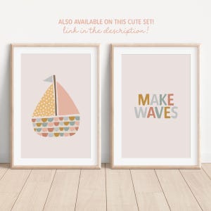 May include: Two framed art prints with a light pink background. One print features a sailboat with a yellow dotted sail, pink sail, and colorful details. The other print says "MAKE WAVES" in colorful letters. The text "ALSO AVAILABLE ON THIS CUTE SET! link in the description!" is at the top.