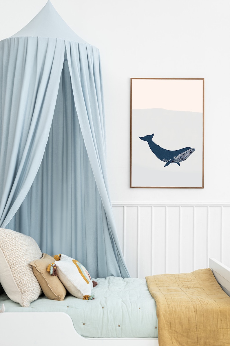 May include: A light blue canopy bed with a white and yellow patterned pillow and a mustard yellow quilt. A framed print of a blue whale is hanging on the wall above the bed.