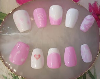 Ataúd corto rosa y blanco con puntas francesas y espirales, además de corazones.