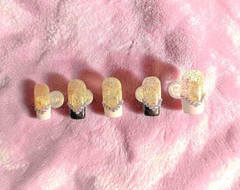 Purpurina dorada con punta francesa blanca y negra y detalles brillantes.