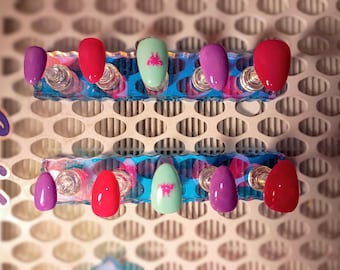 Unhas postiças amendoadas nas cores menta, rosa e roxo, com borboletas nos dedos do meio.