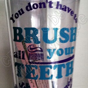 May include: A clear plastic tumbler with a purple, blue, and teal design that reads "You don't have to brush all your teeth, just the ones you want to keep."