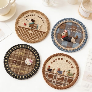 Puede incluir: Cuatro posavasos redondos y tejidos con diseños bordados. Uno presenta un cachorro con el texto "LOVELY PUPPY". Otro dice "super cute puppy". El tercero tiene "LUCKY KITTY". El último dice "SUPER CUTE" y "have a good time everyday".