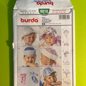 Op de afbeelding: Burda naaipatroon nummer 9810 voor het maken van hoeden en petten voor baby's. Het patroon bevat instructies voor het maken van vijf verschillende hoedstijlen, waaronder een zonnehoed, een baseballpet en een matrozenpet. Het patroon is gedrukt op een witte achtergrond met zwarte tekst en illustraties.