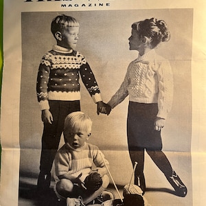 May include: Black and white photo of two children wearing knitted sweaters. The children are standing and sitting, holding yarn and knitting needles. The photo is from a magazine called "This Week".