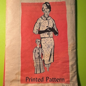 May include: Vintage printed sewing pattern featuring illustrations of a woman and a girl in dresses. The pattern is on a red background with the text "Printed Pattern" and the size 24 1/2. The paper has a beige color.