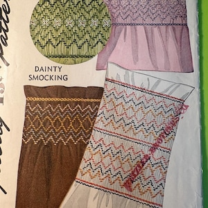 May include: An illustration of smocking patterns in green, pink, brown, and white. The image includes a circular design, a top, and a skirt-like design, all showcasing detailed embroidery. The text "DAINTY SMOCKING" is also visible.