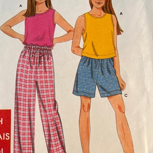 Może przedstawiać: Dwie ilustracje dziewcząt w bezrękawnikach i spodniach do spania. Dziewczyna po lewej stronie ma na sobie różowy top i czerwono-białe spodnie w kratę. Dziewczyna po prawej stronie ma na sobie żółty top i niebiesko-białe wzorzyste spodenki. Obie dziewczyny noszą sandały.