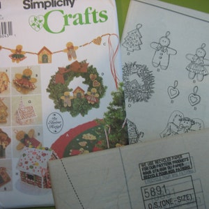 Könnte beinhalten: Ein Nähmuster von Simplicity Crafts für ein Lebkuchenhaus, einen Kranz und Dekorationen. Das Muster enthält Anleitungen zum Nähen eines Lebkuchenhauses, eines Kranzes mit Lebkuchenmännern und einer Vielzahl von Dekorationen, darunter Lebkuchenmänner, ein Baum und ein Herz.