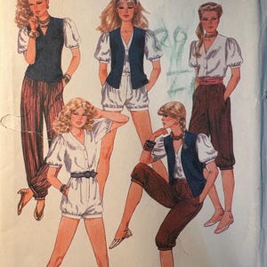 May include: A vintage McCall's sewing pattern from 1982 featuring illustrations of women's fashion designs. The designs include blouses with puff sleeves, vests, shorts, and pants. The pattern is designed by Willi Smith.