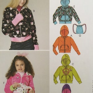 May include: Image of a sewing pattern for children's hoodies. The pattern includes several designs, including a black hoodie with a floral and skull print, a pink jacket, and other colorful options. The text "ONE EASY PATTERN 6 GREAT LOOKS" is visible.