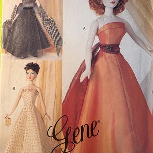 May include: Three fashion dolls in elegant gowns. One doll wears an orange strapless gown with a burgundy sash. Another doll is in a beige patterned dress, and the third doll is in a black and white checkered dress with matching sleeves. The word "Gene" is written in cursive.