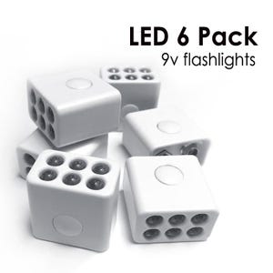 May include: A collection of six white LED flashlights, each cube-shaped with multiple small, dark-colored LED lights. The text "LED 6 Pack 9v flashlights" is displayed in black.