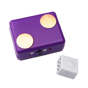 May include: A rectangular purple electronic device featuring two circular gold-colored contact points on the top surface, a black sliding switch, two small screws, and a tiny red indicator light, accompanied by a separate white cube-shaped component.