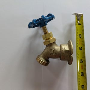 Puede incluir: Un grifo de latón para exteriores con un mango azul. El grifo mide aproximadamente 10 cm de largo, medido con una cinta métrica amarilla. El grifo está diseñado para el acceso al agua en exteriores.
