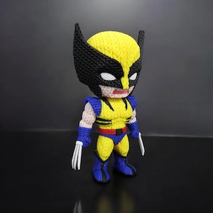 Può includere: Una figura fatta a mano di Wolverine, con un costume giallo e blu con dettagli neri. La figura ha una maschera distintiva, artigli e una corporatura muscolosa. La figura è alta circa 15 cm.