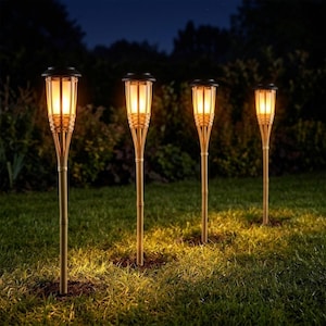 Peut inclure: Quatre torches de jardin solaires d'extérieur avec un extérieur en bambou tressé et une source lumineuse chaude et brillante au sommet. Chaque torche est montée sur un poteau vertical fin conçu pour être planté dans le sol pour l'éclairage.