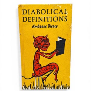 May include: A vintage book titled "DIABOLICAL DEFINITIONS" by Ambrose Bierce. The cover is yellow with black text and a red devil illustration. The devil is reading a black book and sitting on a stool.