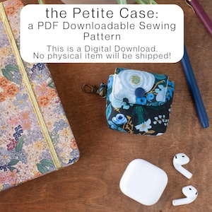 May include: A floral patterned notebook, a small fabric case with a blue and white floral design, a white charging case, and white earbuds are arranged on a wooden surface. The text "the Petite Case: a PDF Downloadable Sewing Pattern" is displayed.