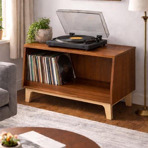 May include: A wooden record player stand with a black turntable and a collection of vinyl records. The stand is brown with light-coloured legs. A houseplant sits on top of the stand. The room has a neutral colour palette.