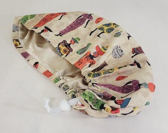 Puede incluir: Un gorro de quirófano abombado con forro de satén beige y un estampado colorido de inspiración africana. El estampado incluye figuras en varios colores, con un cierre de cordón para un ajuste regulable. El gorro está diseñado para profesionales médicos.