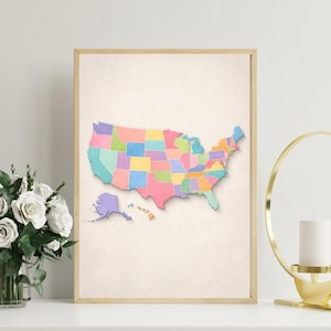 Puede incluir: Un mapa enmarcado de los Estados Unidos, con cada estado en un color pastel diferente. El mapa incluye Alaska y Hawái. El marco es de color madera clara y el fondo es de color beige neutro. La obra de arte se exhibe sobre una superficie blanca.