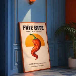 Può includere: Un poster incorniciato con le parole "FIRE BITE" e un'illustrazione di un peperoncino rosso. Il poster ha uno sfondo beige con un bordo arancione ed è appoggiato a un muro blu. È visibile anche il testo "HANDLE WITH ATTITUDE" e "HEAT LEVEL: UNLOCKED PROCEED IF YOU DARE".