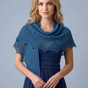 Può includere: Una donna indossa uno scialle blu lavorato a maglia con collo a cappuccio e dettagli in pizzo intricati. Lo scialle è drappeggiato su un vestito blu scuro. I bordi dello scialle hanno un design smerlato. Lo sfondo è blu chiaro.