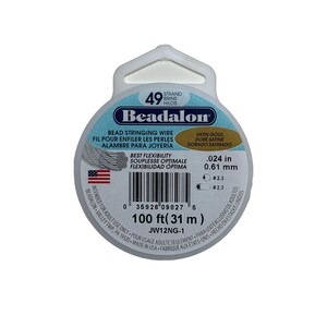 May include: A spool of Beadalon satin gold bead stringing wire. The package includes 100 ft (31 m) of .024 in (0.61 mm) wire, with a best flexibility rating. The label features the brand name, product details, and the American flag.