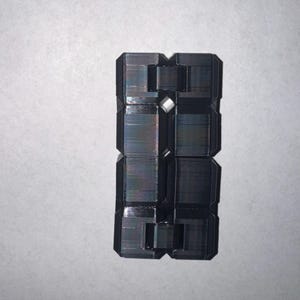 May include: A black, geometric, rectangular object with a complex, multi-faceted design. The object appears to be made of a solid material with a slightly reflective surface. The design features a series of interconnected rectangular and square shapes.