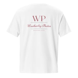 May include: A white t-shirt with the text "WP Weatherby Photos" printed on the back in a mauve color. The text is arranged in two lines with the initials "WP" at the top and the business name below.