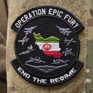 May include: A black embroidered patch with the text "OPERATION EPIC FURY" and "END THE REGIME". The patch features a map of Iran in the colors of the Iranian flag, surrounded by gray fighter jets.