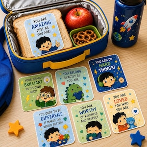 Puede incluir: Una lonchera azul con un sándwich, una manzana y pretzels. Incluye pegatinas motivacionales con frases como "You are Amazing" y "You Can Do Hard Things!" También hay una botella de agua azul con un diseño de cohete.