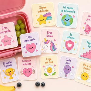 Könnte beinhalten: Eine Sammlung farbenfroher, illustrierter Karten mit positiven Affirmationen und niedlichen Charakteren wie Sternen und Herzen. Die Karten sind auf Spanisch und liegen in der Nähe einer rosa Lunchbox, Trauben, einer Banane und Blaubeeren.