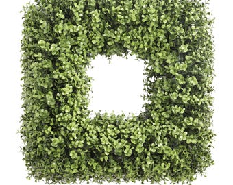 May include: A square-shaped artificial boxwood wreath featuring dense, vibrant green foliage with small, rounded leaves. The wreath has a hollow center and a uniform, structured frame, creating a thick, textured appearance of lush greenery.
