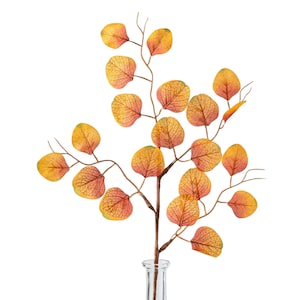 May include: A decorative artificial branch featuring numerous rounded leaves in shades of yellow, orange, and red. The leaves display a visible vein pattern and are attached to a thin, brown, branching stem that extends into a clear glass vase.
