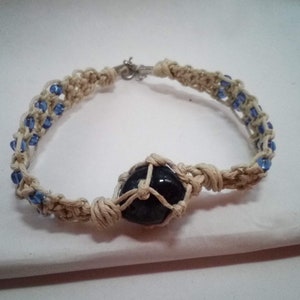 May include: A white macrame bracelet with a dark blue stone bead and blue glass beads.